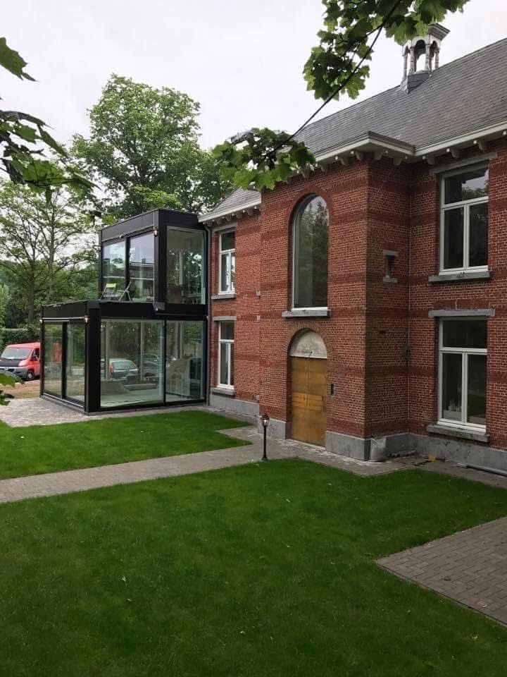 Glazen aanbouw aan rood bakstenen herenhuis vanuit een andere hoek