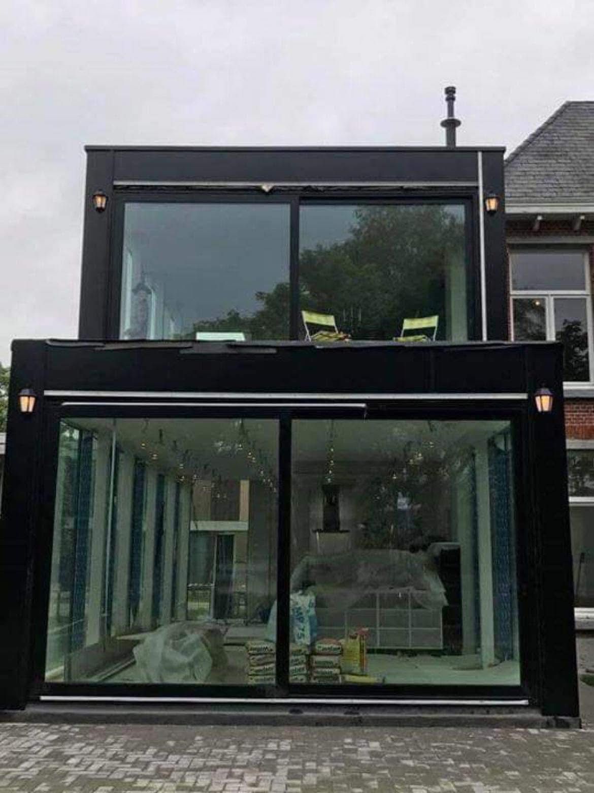 Frontaal aanzicht van zwart-aluminium glazen aanbouw met schuifdeuren